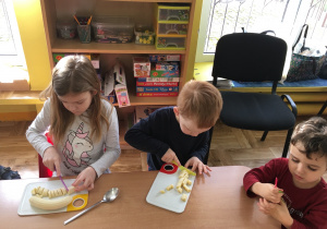 dzieci kroją banany na plastikowych tackach
